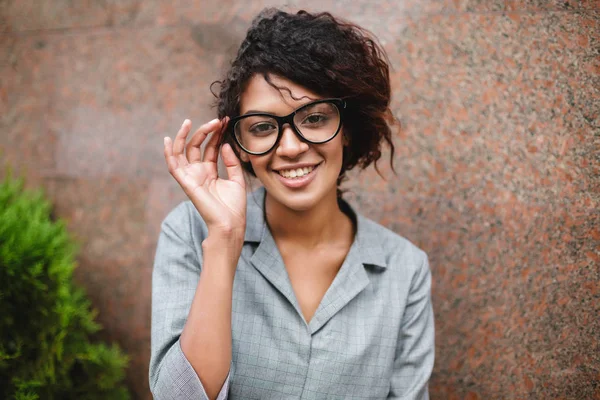 Vakker afroamerikansk jente med briller, ser gladelig i kamera isolert – stockfoto