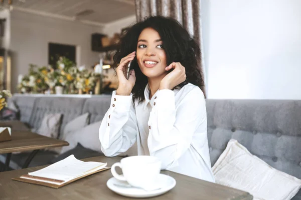 Mladá africká americká dívka sedí v restauraci a mluví na mobil — Stock fotografie