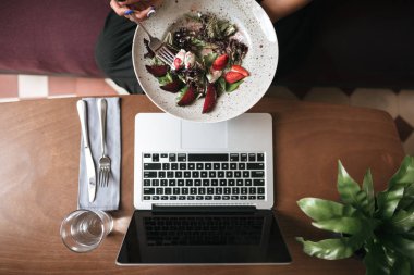 Fotoğraf salatası el ve cam bıçak ve çatal Restoran tablo ile kapatın. Salata ve kafede masada dizüstü fotoğrafı