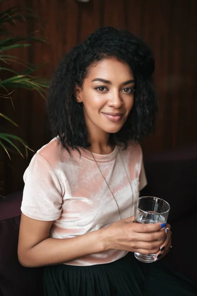 Портрет молодой красивой афроамериканской девушки, сидящей в ресторане и смотрящей в камеру . — стоковое фото
