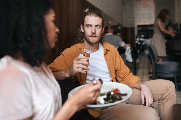 Homem legal sentado no restaurante e conversando com a menina. Menino sentado no café com copo de água na mão — Fotografia de Stock