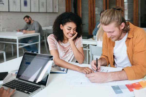 Beautiful African American lady with dark curly hair and cool boy with blond hair sitting in classroom and studying together