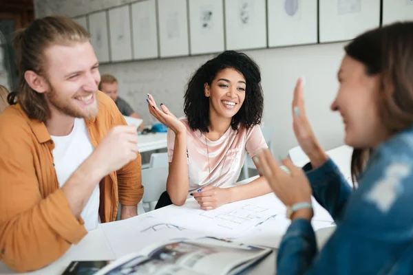 Gruppo di studenti che studiano insieme in classe. Ragazzo e due ragazze felicemente guardarsi mentre discutono qualcosa — Foto Stock