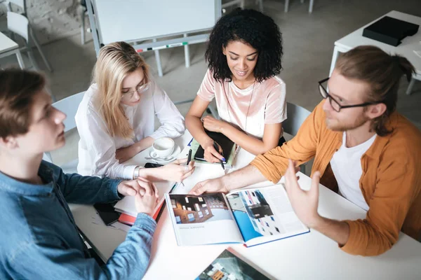 Retrato de jóvenes sentados en el cargo discutiendo algo. Grupo de chicos guays trabajando en un nuevo proyecto mientras están sentados en la cafetería — Foto de Stock