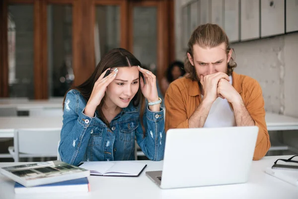 Retrato jovem homem e menina cansadamente olhando no laptop enquanto trabalham juntos no escritório — Fotografia de Stock