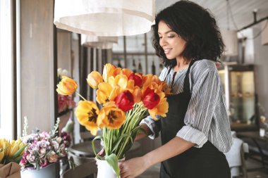 Renkli Lale buketi oluşturma önlük güzel çiçekçi. Siyah kıvırcık saçlı çiçeklerle çalışma oldukça Afro-Amerikan kız