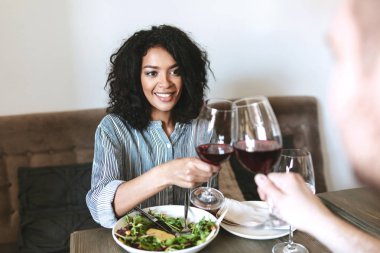 El ve salata masada kırmızı şarap ile restoranda genç Afro-Amerikan kız portresi