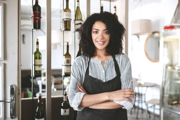 무기와 앞치마 서에서 아름 다운 아프리카계 미국인 여자는 레스토랑에서 접혀. 카페 앞치마에 서 있는 검은 곱슬 머리와 어린 소녀 — 스톡 사진