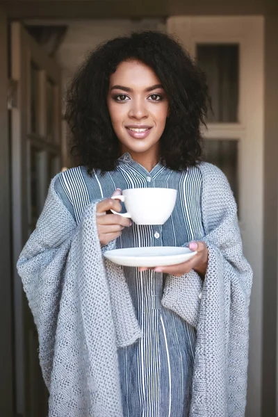 Gülümseyen Afro-Amerikan kız portresi ekose elinde kahve ile sarılı. Kahve içme siyah kıvırcık saçlı güzel Bayan — Stok fotoğraf