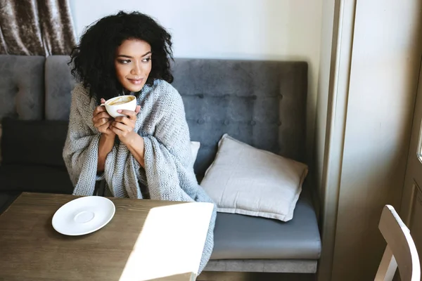 Genç Afro-Amerikan kız restoranda kahve içme. Sersem Kupası elinde ile pencereden dışarı bakarak siyah kıvırcık saçlı güzel kadın portresi — Stok fotoğraf