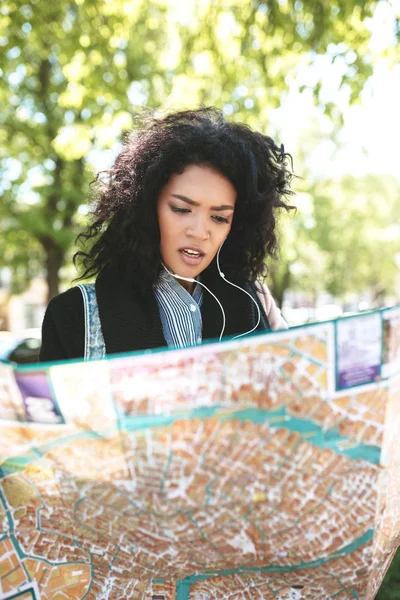 Ung afroamerikansk jente som står på gata og prøver å finne riktig retning på kartet – stockfoto