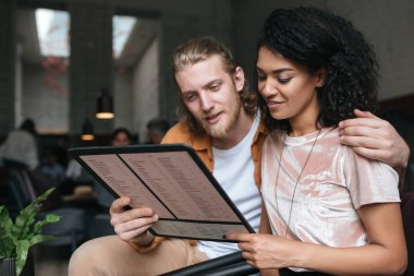 Elinde menüsüyle restoranda oturan genç güzel çift portresi