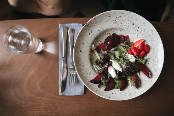 Cerrar foto de ensalada con cuchillo y tenedor en la mesa en el restaurante. Foto de ensalada y vaso de agua en la mesa en la cafetería — Foto de Stock