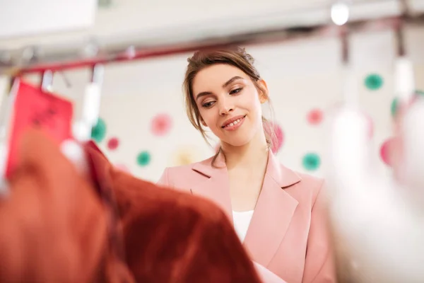 Fiatal lány rózsaszín kabát és fehér póló, álmodozva nézett a rack, ruhák divat boutique — Stock Fotó