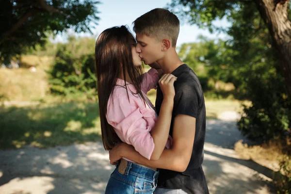 Retrato de jovem casal bonito abraçando e beijando uns aos outros enquanto em pé no parque — Fotografia de Stock