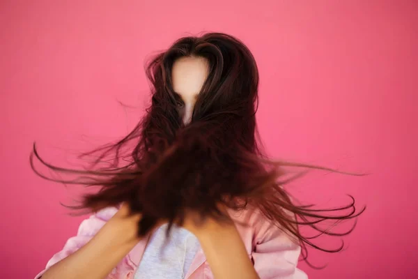Портрет красивой девушки с темными длинными волосами, стоящими на розовом фоне изолированы — стоковое фото