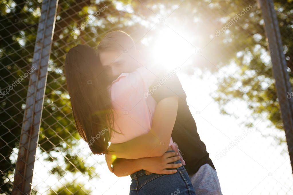 Beautiful photo of young thoughtful boy standing and embracing pretty girl while spending time in park