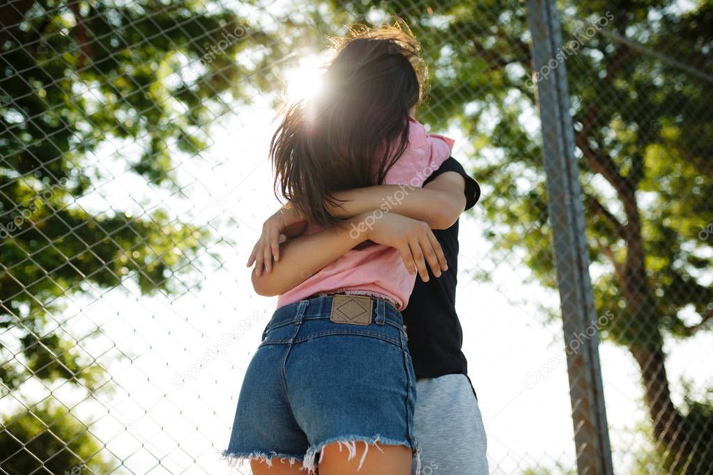 Portrait of young beautiful couple standing and embracing one another in park