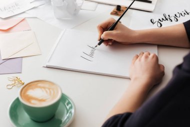 Beautiful photo of woman hands holding classic ink pen while writing notes on white desk clipart
