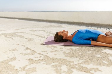Yoga mat ve eğitim yoga yalan karanlık sıralama saçlı genç kadın sersem gözleri kapatılması sırasında teşkil etmektedir. Meditasyon ve yoga izole uygulamak mavi mayolu güzel Bayan portresi