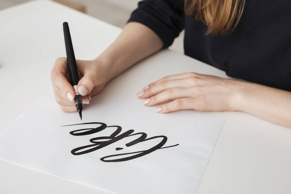 Close up photo of young woman hands writing on paper on desk  isolated