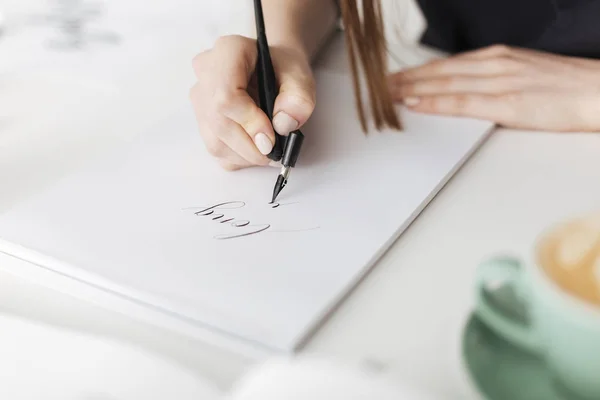 Cerca de la foto de las manos de la mujer sosteniendo la pluma y escribir hermosas notas en papel aislado —  Fotos de Stock