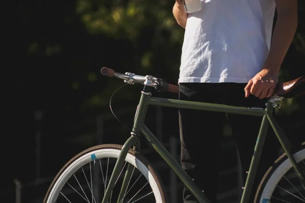 Close up photo of man body in white t-shirt holding bicycle . Photo of man body standing with classic dark green bicycle — Stock Photo, Image