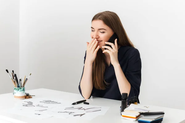 Portré, fiatal aranyos hölgy ül a fehér íróasztal, és beszél vele mobiltelefon csövéhez boldogan elszigetelt — Stock Fotó