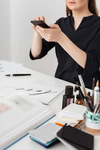 Retrato bela senhora sentado na mesa branca e tirar fotos de notas em seu celular isolado — Fotografia de Stock