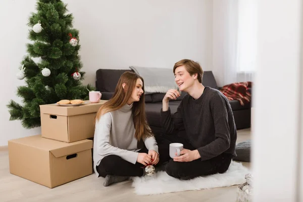 Portré, fiatal, gyönyörű pár emelet otthon ül, és beszél egymással, miközben díszítése az új év tree — Stock Fotó
