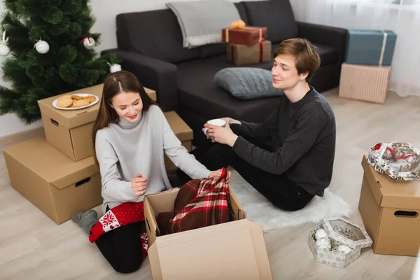 Portré, szép lány álmodozva megüresedett állás a doboz ülve fiú a gazdaság bögre emelet otthon a karácsonyfa háttér — Stock Fotó