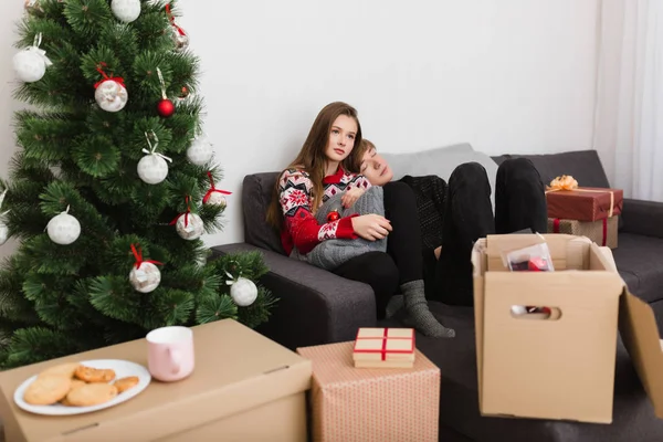 Noel ağacının yanında birlikte vakit ise evde koltukta oturan güzel genç çiftin fotoğrafı — Stok fotoğraf