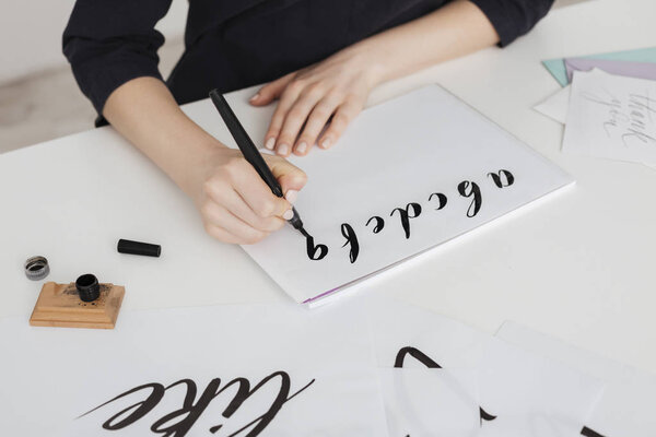 Закрыть фотографию молодой женщины руки написания алфавита на бумаге на столе изолированы
