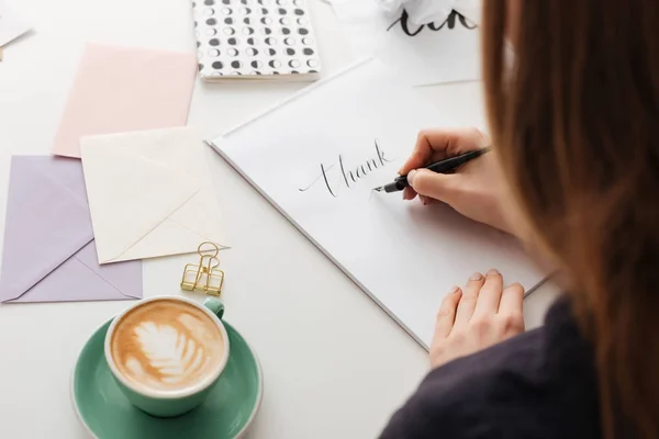 Hermosa foto de la mujer de la parte trasera sentada en el escritorio blanco y notas de escritura aisladas —  Fotos de Stock