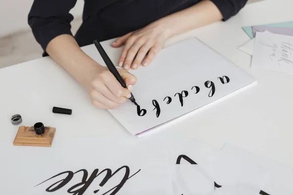 Tutup foto tangan wanita muda menulis alfabet di atas kertas di atas meja terisolasi Stok Gambar