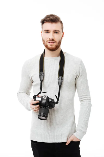 Knappe bebaarde jonge man kijkend naar de camera met Dslr camera opknoping op de hals geïsoleerd — Stockfoto