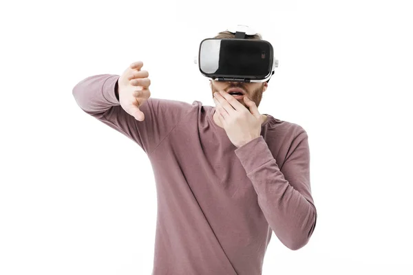 Retrato de jovem homem surpreso usando óculos de realidade virtual no fundo branco. Menino pensativo brincando com óculos de realidade visual isolados — Fotografia de Stock