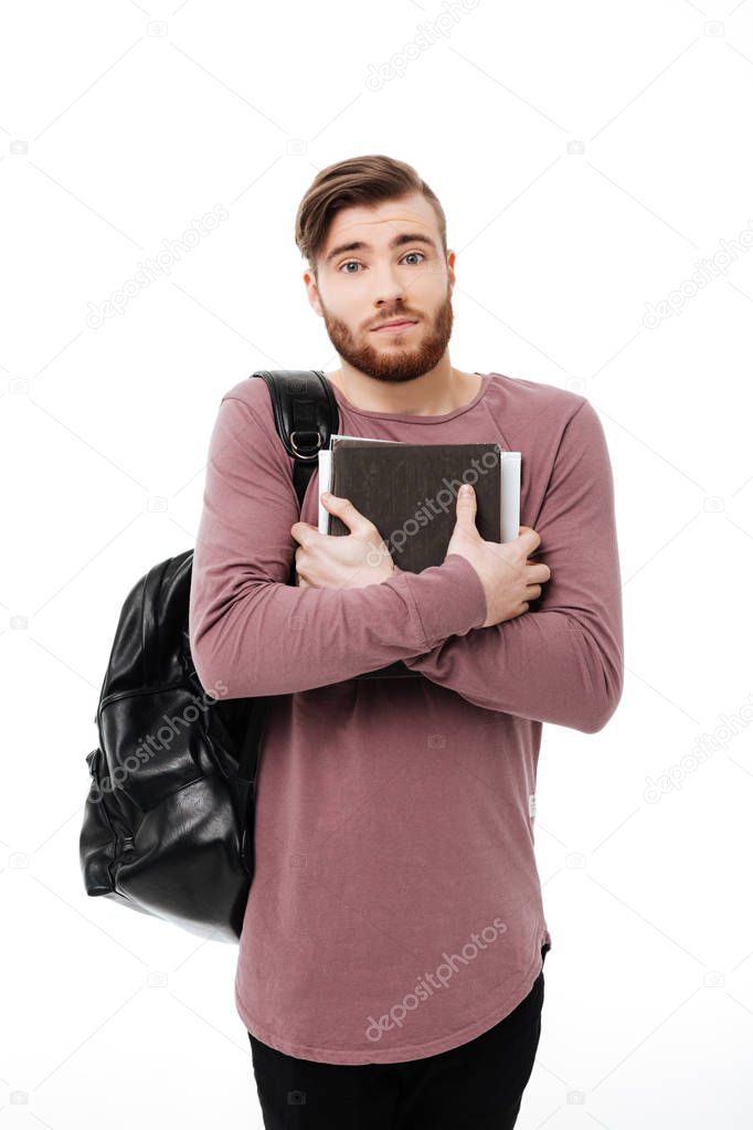 Embarrassed male student carrying books and a backpack isolated