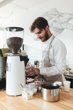Genç adam çalışma bardaki kahve makinesi ile restoranda karşı. Barista kahve kahve makinesi café'de önlük ve Beyaz gömlekli. Kafede barista olarak çalışan bir çocuk 