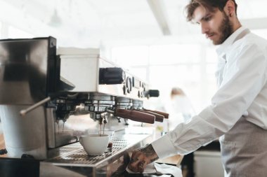 Kahve makinesi kahve dükkanında çalışan düşünceli adam. Genç barista kahve kahve makinesi restoranda kontuarında önlük ve Beyaz gömlekli. Barista café'de çalışan bir çocuk