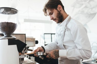 Kahve makinesi ile barda çalışan genç adam portresi kafede karşı. Barista kahve kahve makinesi restoranda önlük ve Beyaz gömlekli. Barista café'de çalışan bir serin çocuk