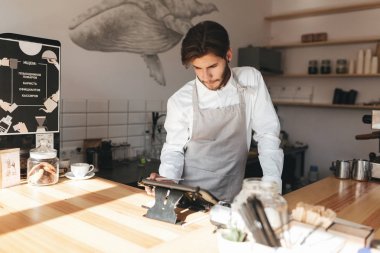 Genç barista kahve dükkanında nakit sayaç kullanarak önlük ve Beyaz gömlekli. Düşünceli adam Terminal ile kasada Restoran onun işyerinde çalışma