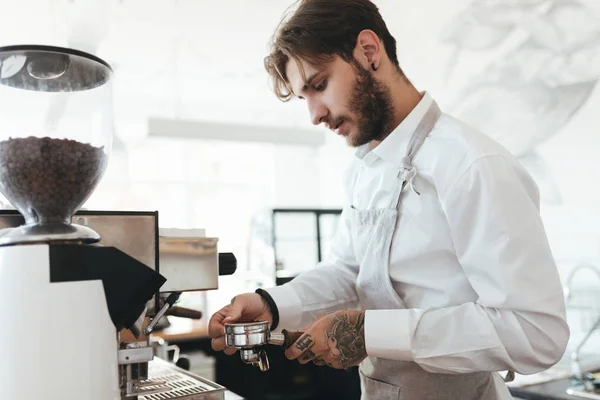 Ritratto di giovane che lavora con la macchina da caffè al bancone del bar in caffetteria. Barista in grembiule e camicia bianca che fa il caffè dalla macchina del caffè nel ristorante. Ragazzo figo che lavora come barista al bar — Foto Stock