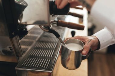 Barista kahve kahve dükkanında kasaya hazırlanıyor. Adam el kahve kahve makinesi restoranda için süt kırbaçlanan kapatın