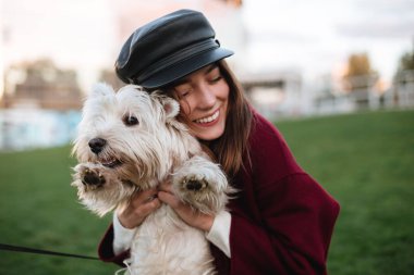 Siyah kap ve onun küçük sevimli köpek parkında da vakit sarılma ceket genç güzel Bayan portresi