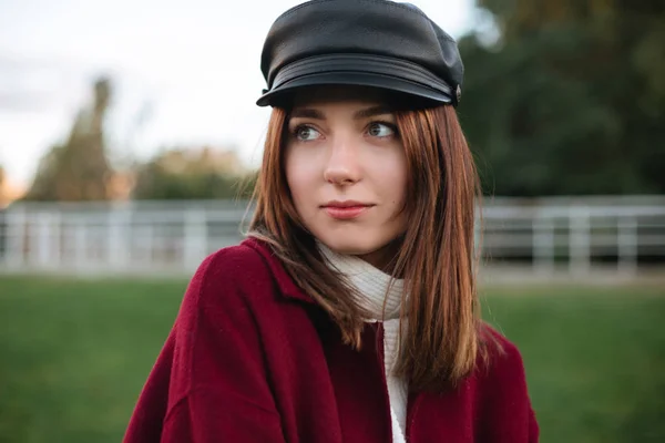 Портрет милой дамы в черной шапке и пальто, стоящих в парке и задумчиво глядя в сторону изолированных — стоковое фото