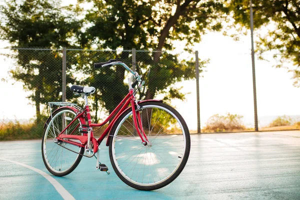 Zbliżenie zdjęcie czerwony rower klasyczny stojący na boisko do koszykówki w parku. Piękne zdjęcie roweru na białym tle — Zdjęcie stockowe