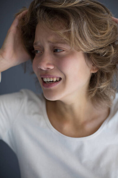 Portrait of young crying woman frightenedly looking aside isolated