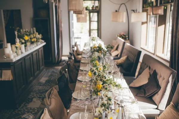 Restaurant interior. Wedding banquet. Table for guests, decorated with candles and flowers, served with cutlery and crockery and covered with a tablecloth. Restaurant entrance