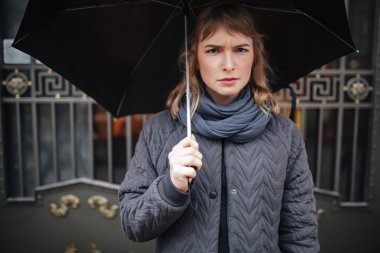 Siyah şemsiye ile sokakta duran ve ne yazık ki kamera izole bakarak üzgün Bayan portresi